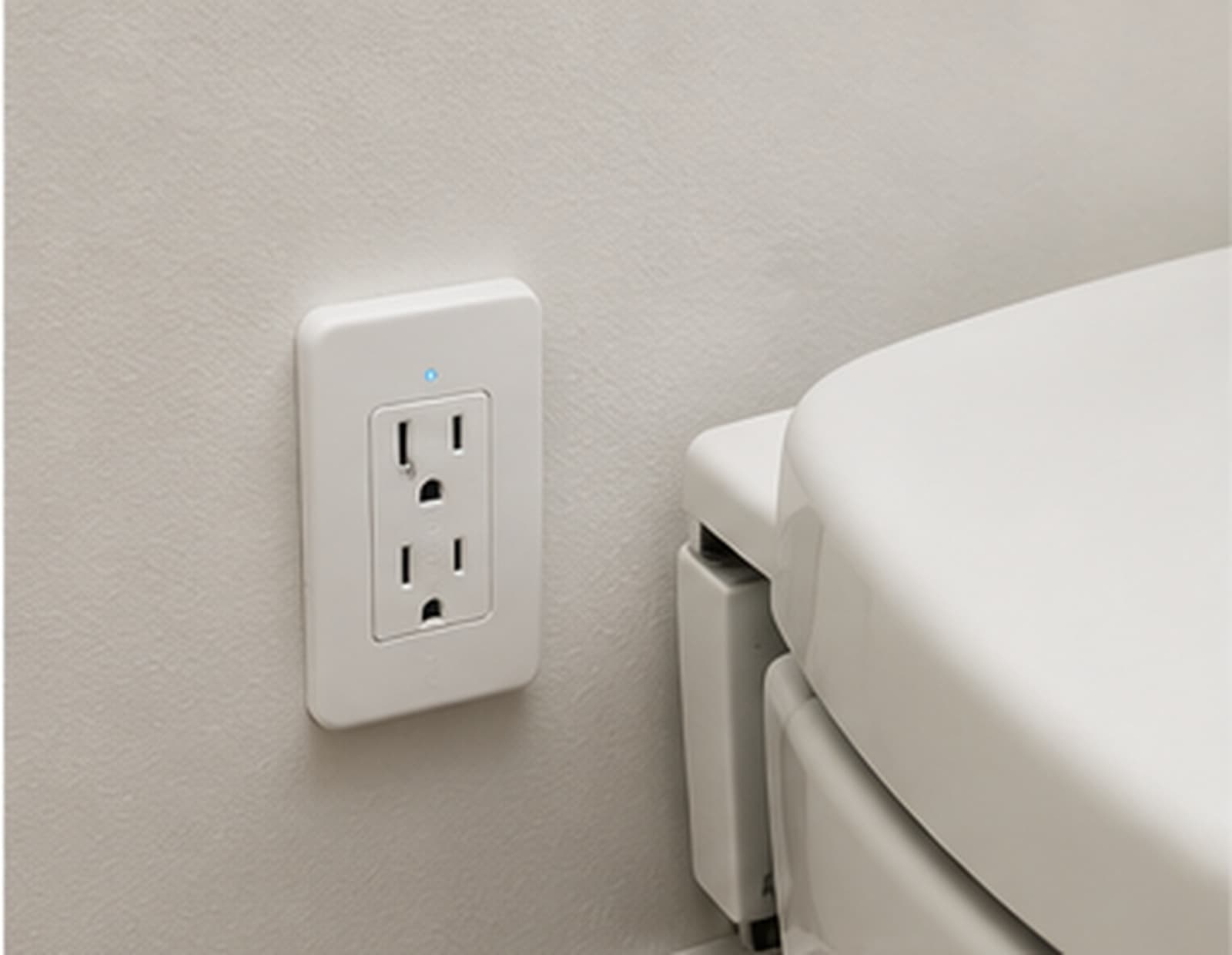 A wall outlet installed beside a smart toilet in a bathroom